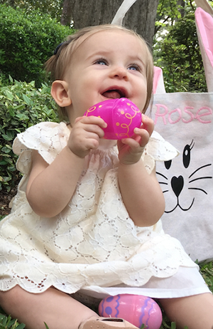 Photo of a baby girl at Easter with 'Rose' stitched on her bag